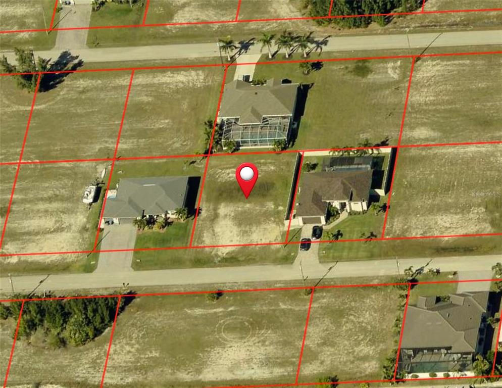 This aerial view shows a vacant residential lot situated between two existing houses — 4621 NW 33RD TERRACE, CAPE CORAL, FL