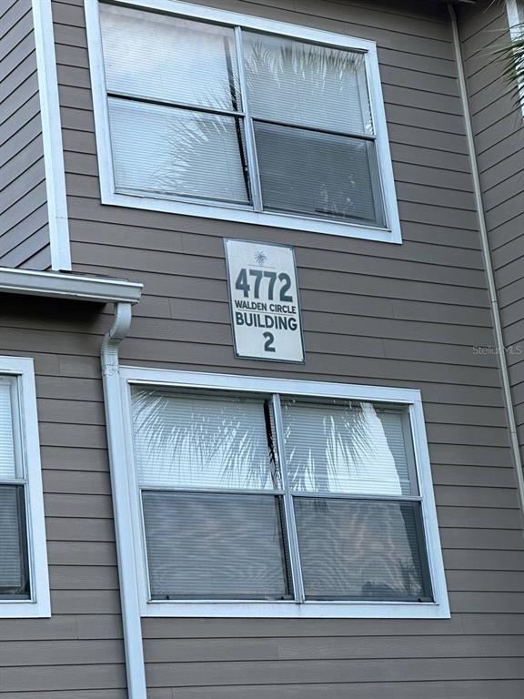 The exterior of a multi-story building features gray horizontal siding and two large windows — 4772 WALDEN CIRCLE UNIT 11, ORLANDO, FL