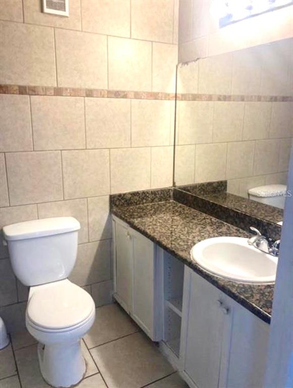 A bathroom features a white toilet, a granite vanity countertop, and light-colored wall tiles — 4772 WALDEN CIRCLE UNIT 11, ORLANDO, FL