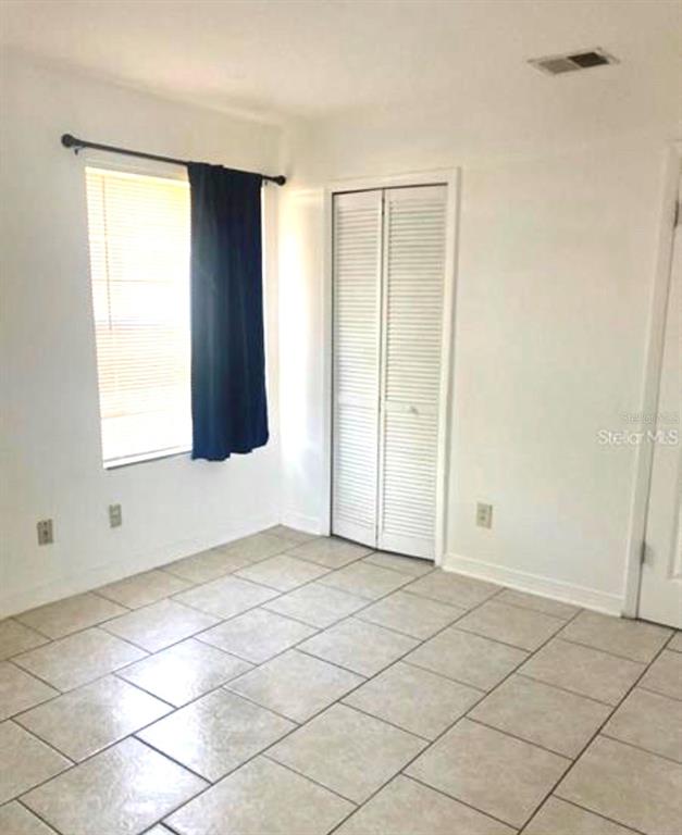 A room with white walls, tiled flooring, a window with a curtain, and a closet — 4772 WALDEN CIRCLE UNIT 11, ORLANDO, FL