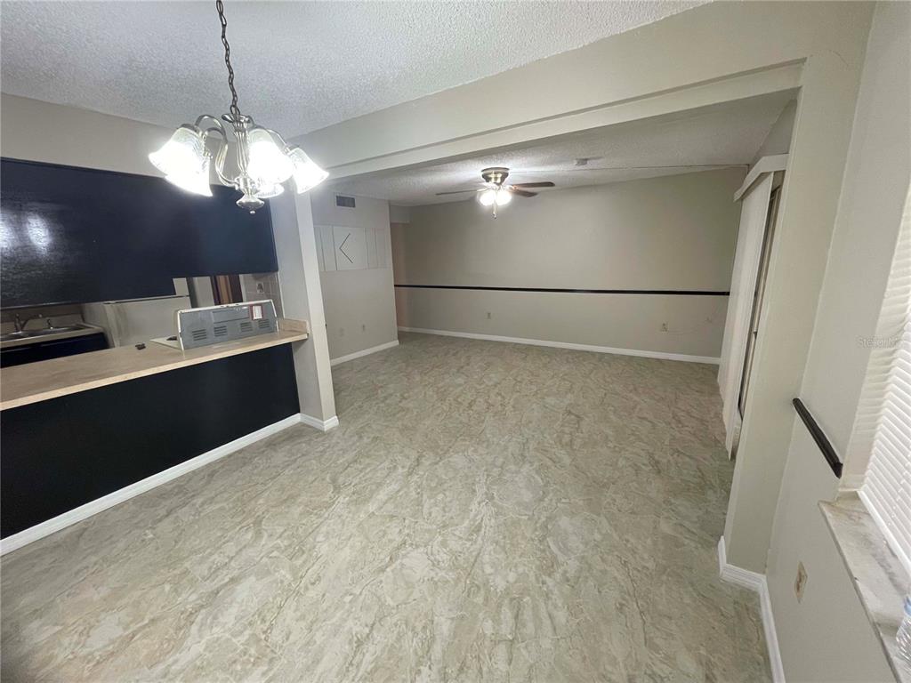 A dining area with a breakfast bar opens into a living room with tile flooring — 1000 LAKE OF THE WOODS BOULEVARD UNIT F106, FERN PARK, FL