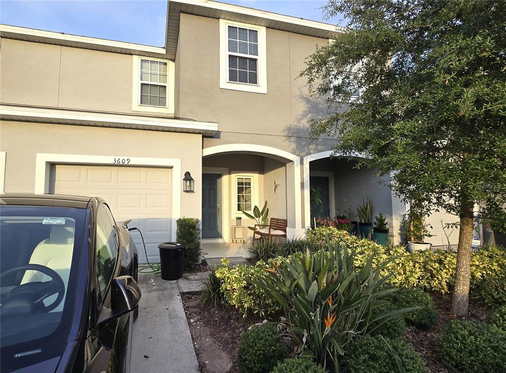 A two-story townhouse exterior features a garage, a covered entryway, and a landscaped front yard — 3609 ANIBAL STREET, KISSIMMEE, FL