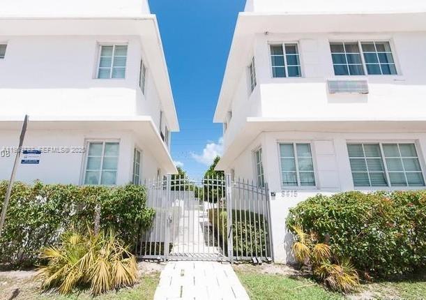 Two white two-story apartment buildings are separated by a central walkway with a metal gate — 8415 Harding Ave # 5, Miami Beach FL 33141, MIAMI BEACH, FL