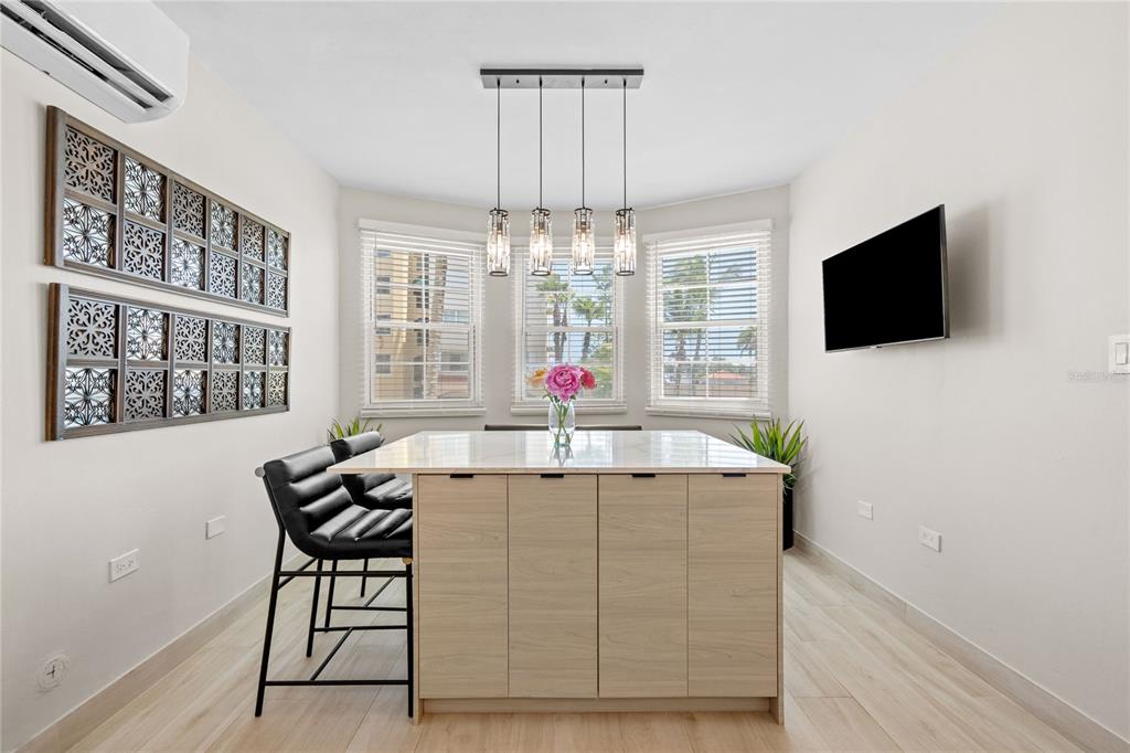 A dining area features a kitchen island, pendant lighting, wall art, and three windows — 6690 Rd. ROYAL PALM COND. UNIT D-101, VEGA ALTA, PR