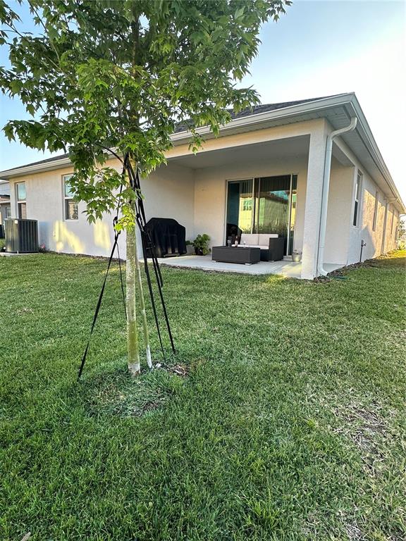 A backyard view shows a covered patio with outdoor furniture and a young staked tree — 14827 MILFOIL AVENUE, ORLANDO, FL