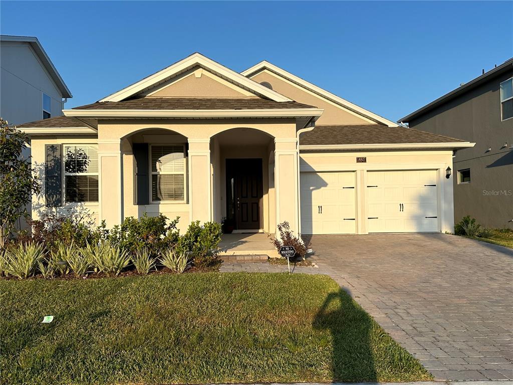 A single-story suburban house features a two-car garage, a covered entryway, and a paved driveway — 14827 MILFOIL AVENUE, ORLANDO, FL