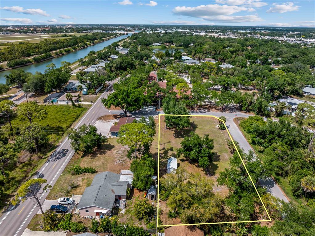 An aerial view shows a vacant, tree-covered lot outlined in yellow next to a house — DAWN DRIVE, VENICE, FL