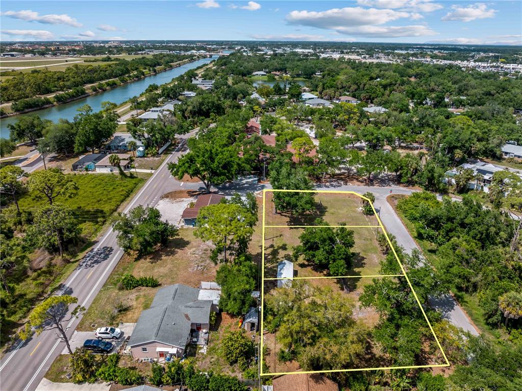 An aerial view shows three adjacent vacant lots outlined in yellow near a road and canal — DAWN DRIVE, VENICE, FL