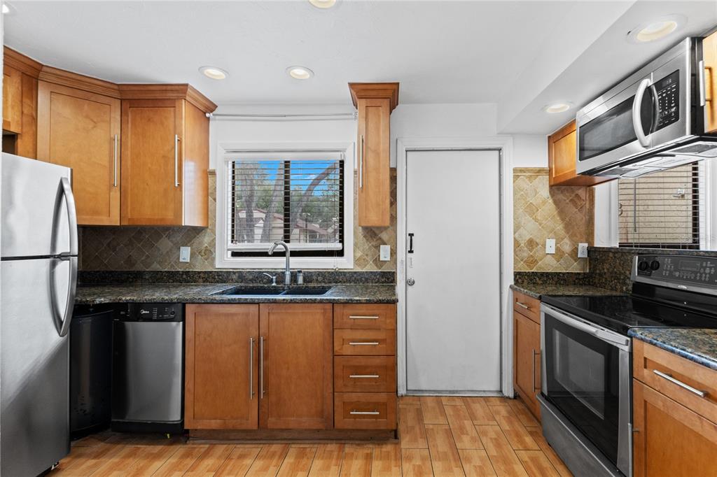 A kitchen features wood cabinets, granite countertops, stainless steel appliances, and a tiled backsplash — 5641 ASHLEY OAKS DRIVE UNIT 37, TAMPA, FL