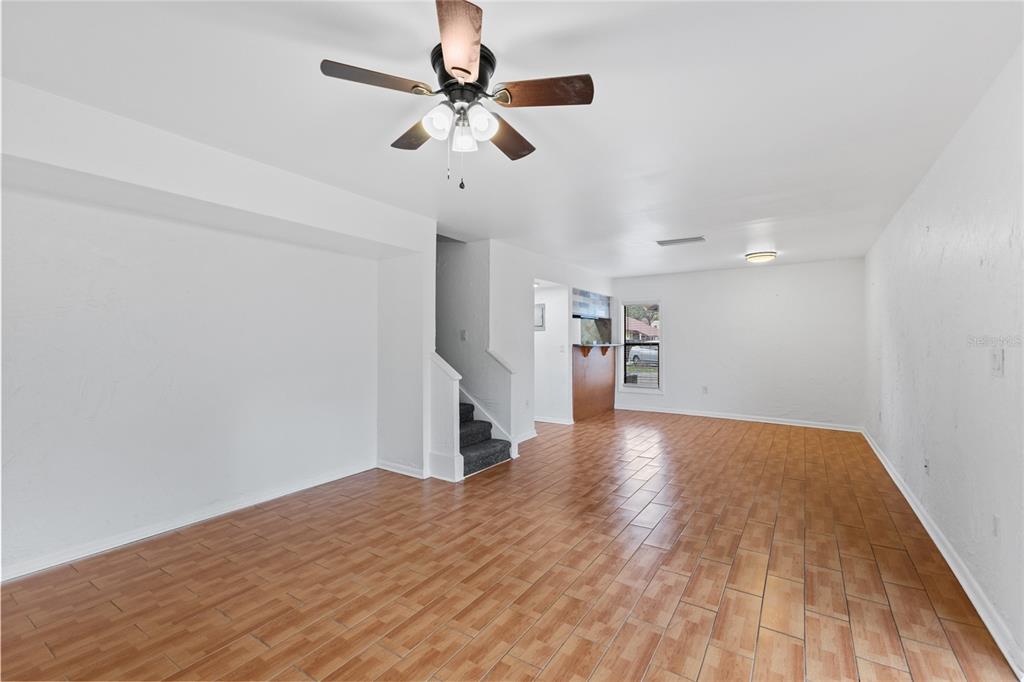 An empty living room features light wood-look tile flooring, white walls, and a ceiling fan — 5641 ASHLEY OAKS DRIVE UNIT 37, TAMPA, FL