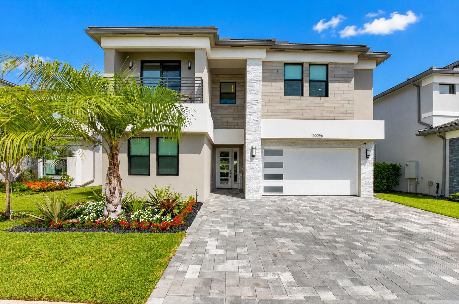 A two-story modern house features a paved driveway, a white garage door, and landscaping — 20056 Hirono Lane, Boca Raton FL 33434, BOCA RATON, FL