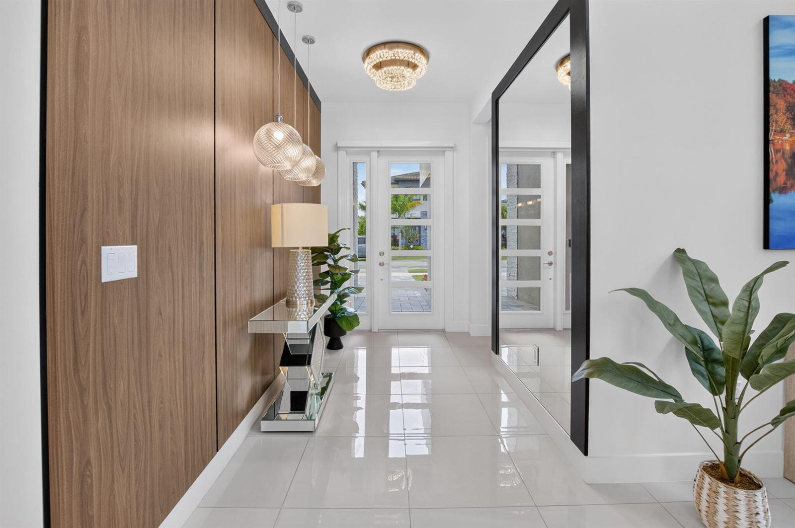 A bright entryway features wood-paneled walls, a mirrored console table, and a large floor-to-ceiling mirror — 20056 Hirono Lane, Boca Raton FL 33434, BOCA RATON, FL