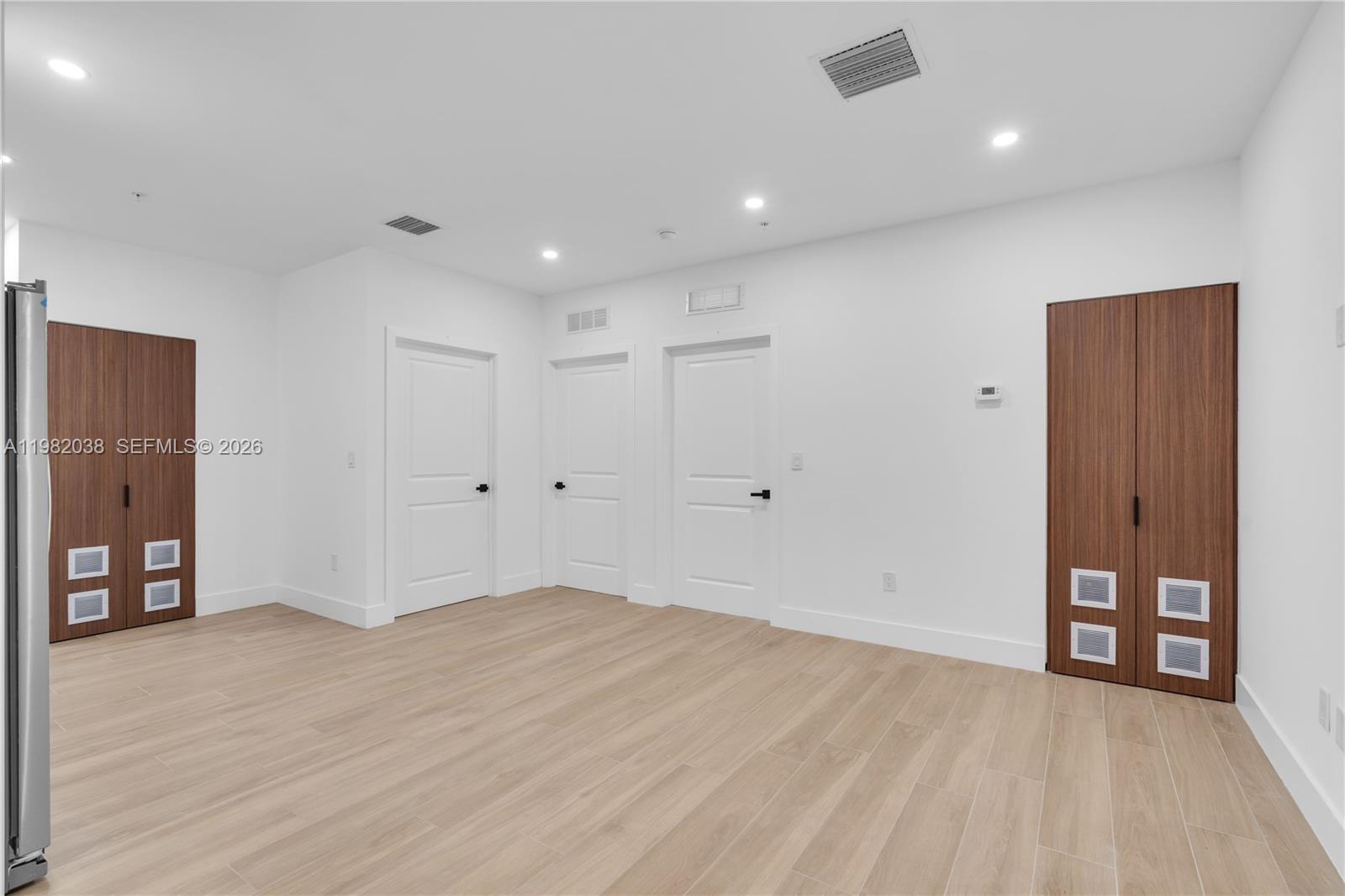 A minimalist room features light wood-look flooring, white walls, and two sets of wood-paneled cabinets — 1037 NW 2nd St # 3C, Miami FL 33128, MIAMI, FL