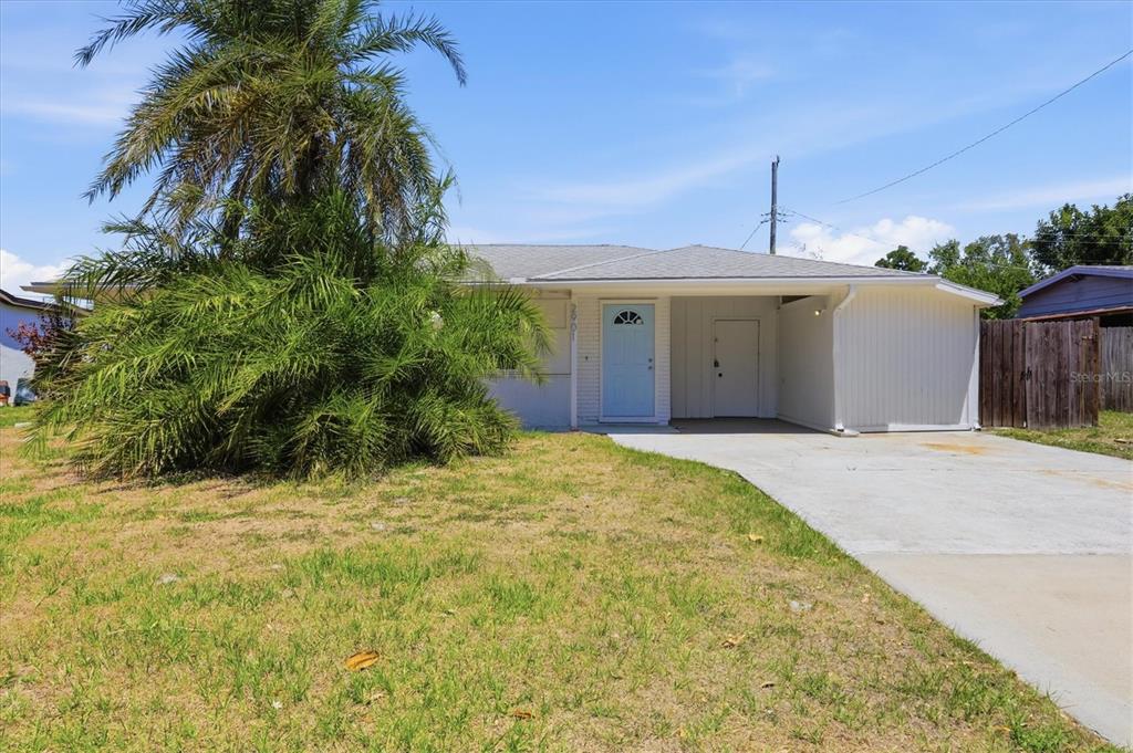 A single-story house with a light blue front door, a carport, and a large palm tree — 2901 POPLAR STREET, SARASOTA, FL
