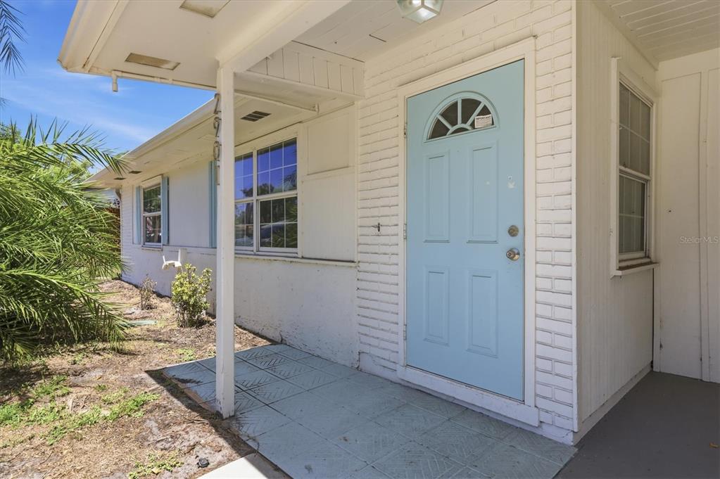 A light blue front door is set into a white brick exterior with a covered porch — 2901 POPLAR STREET, SARASOTA, FL