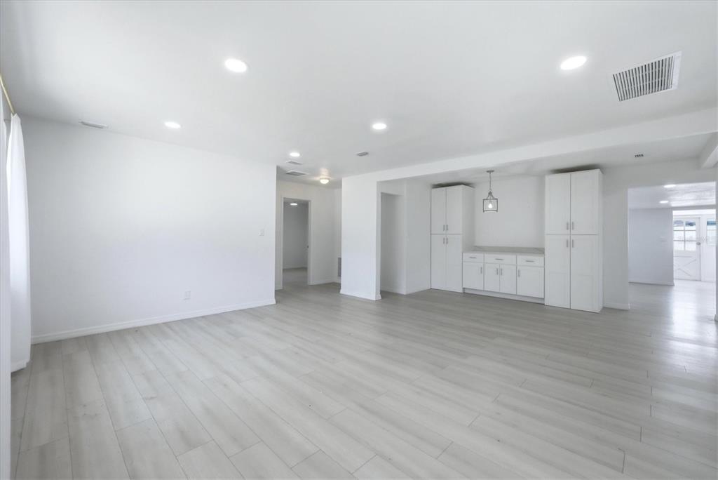 A bright, open-concept room features white walls, light wood-look flooring, and a built-in white cabinet unit — 2901 POPLAR STREET, SARASOTA, FL