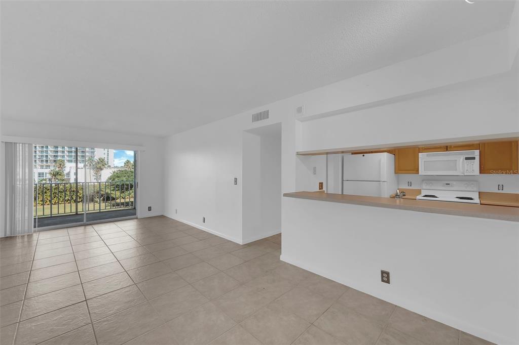An open-concept living area with tile flooring, a breakfast bar, and a sliding glass door — 2875 PALM BEACH BOULEVARD UNIT 205, FORT MYERS, FL