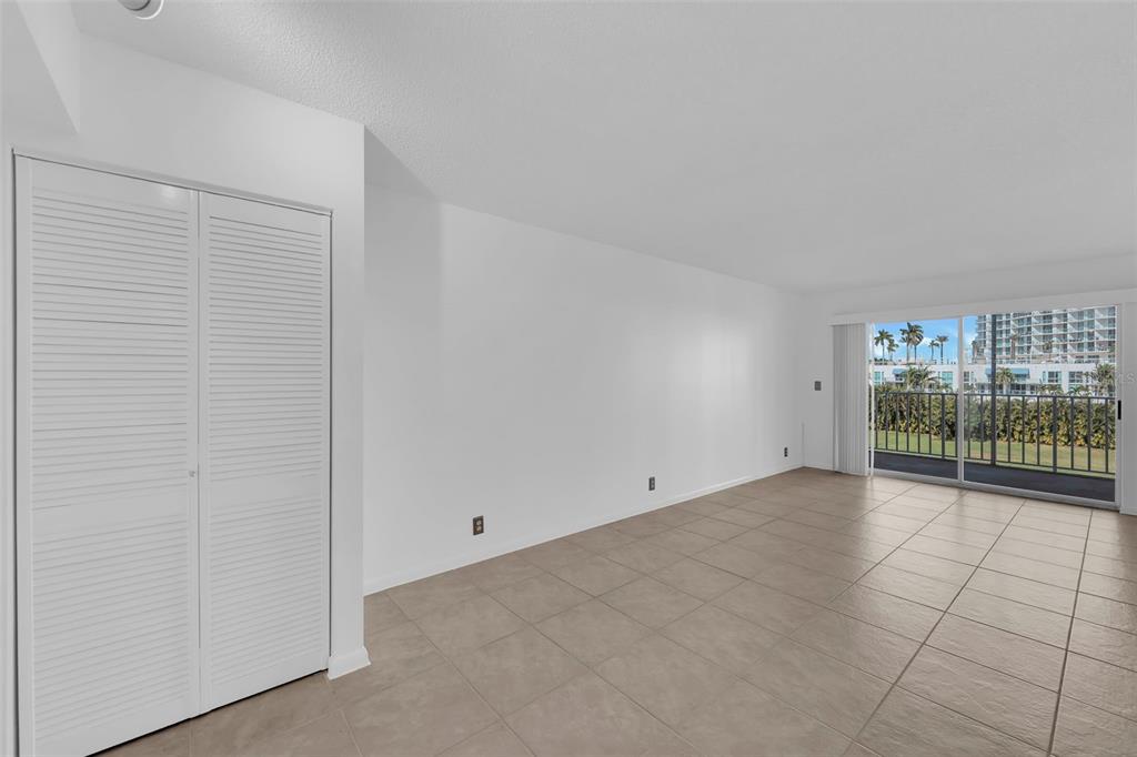 An empty room with white walls, tile flooring, a louvered closet door, and a sliding door — 2875 PALM BEACH BOULEVARD UNIT 205, FORT MYERS, FL