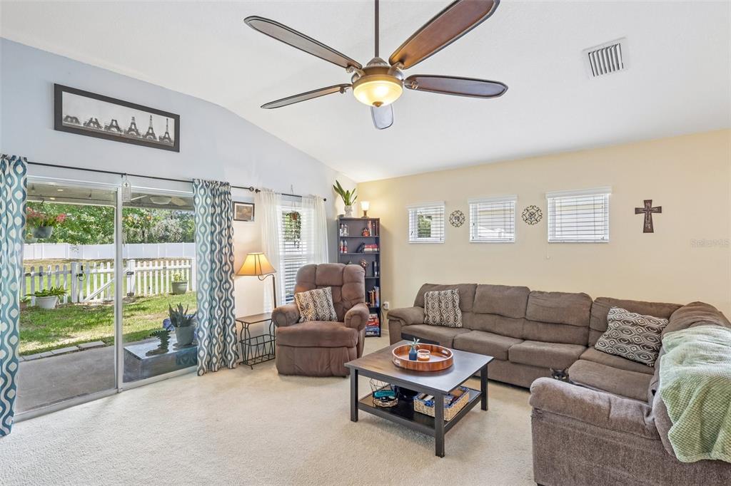 A living room features a sectional sofa, recliner, ceiling fan, and sliding doors to a yard — 14284 FINSBURY DRIVE, SPRING HILL, FL