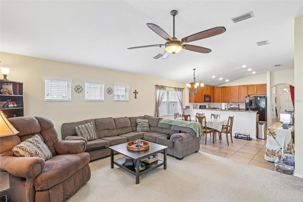 A living room with a sectional sofa and recliner opens to a kitchen with dining area — 14284 FINSBURY DRIVE, SPRING HILL, FL