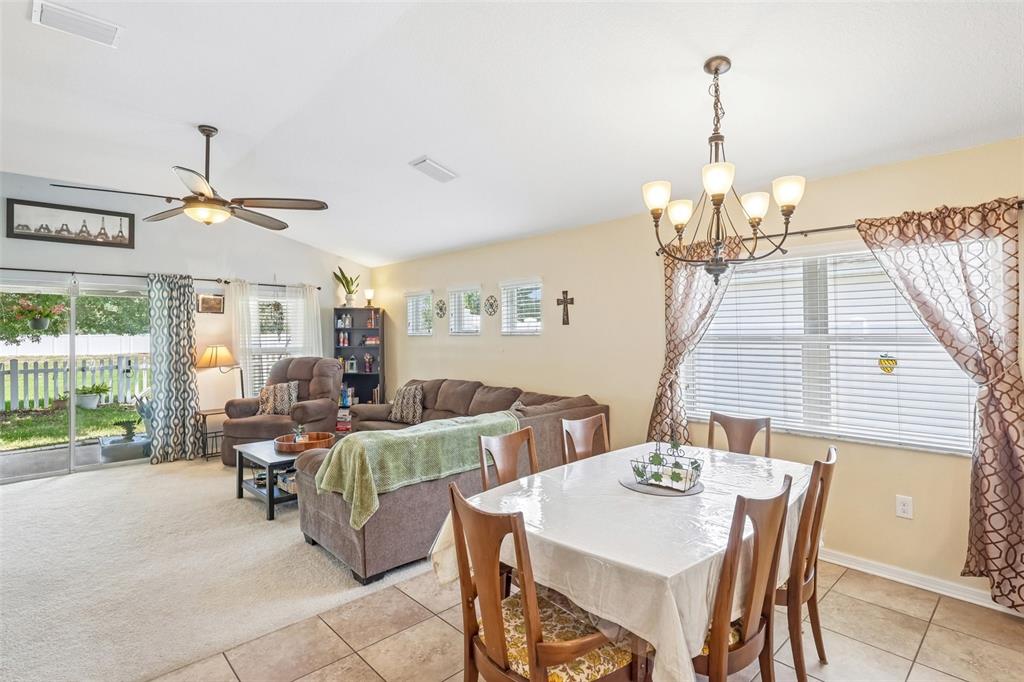 A dining area with a chandelier sits adjacent to a living room with carpeted floors — 14284 FINSBURY DRIVE, SPRING HILL, FL