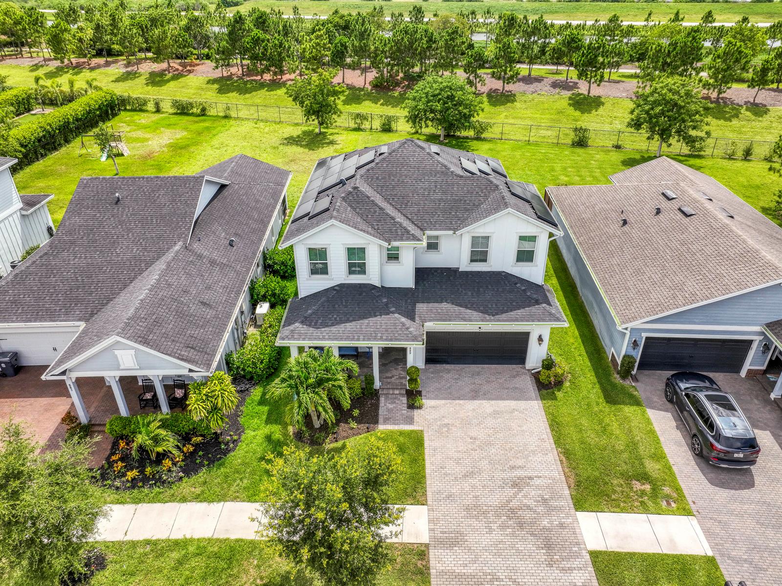 An aerial view shows a two-story suburban house with a dark shingled roof and solar panels — 889 Wandering Willow Way, Loxahatchee FL 33470, LOXAHATCHEE, FL