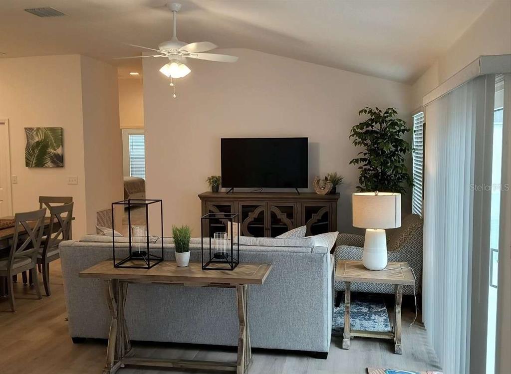 A living room features a gray sofa, a wooden console table, and a television stand — 2845 CHARITY LOOP, THE VILLAGES, FL