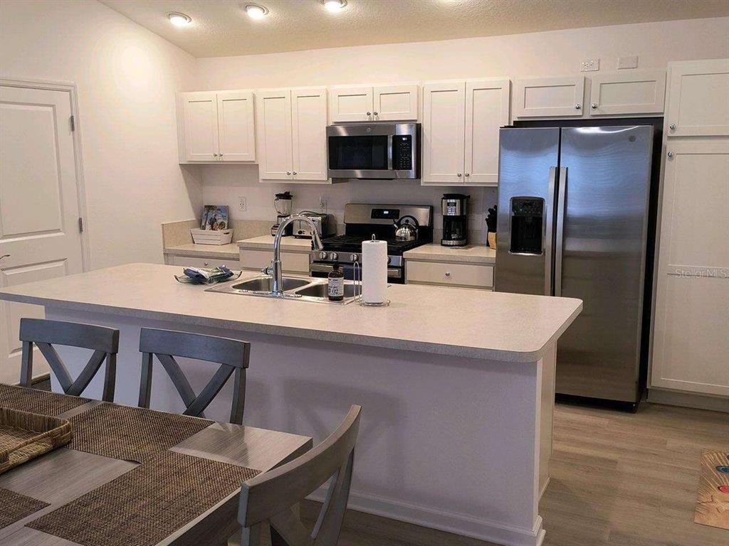 A kitchen features white cabinets, stainless steel appliances, and a large central island — 2845 CHARITY LOOP, THE VILLAGES, FL