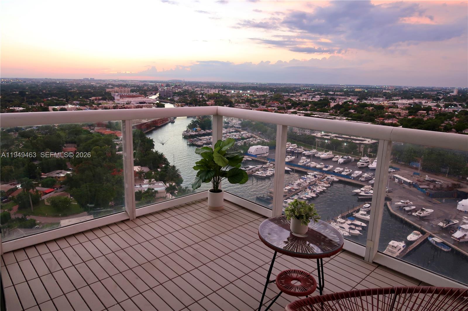 A high-rise balcony features a tiled floor, a small table, and views of a marina — 1861 NW S River Dr # 2505, Miami FL 33125, MIAMI, FL