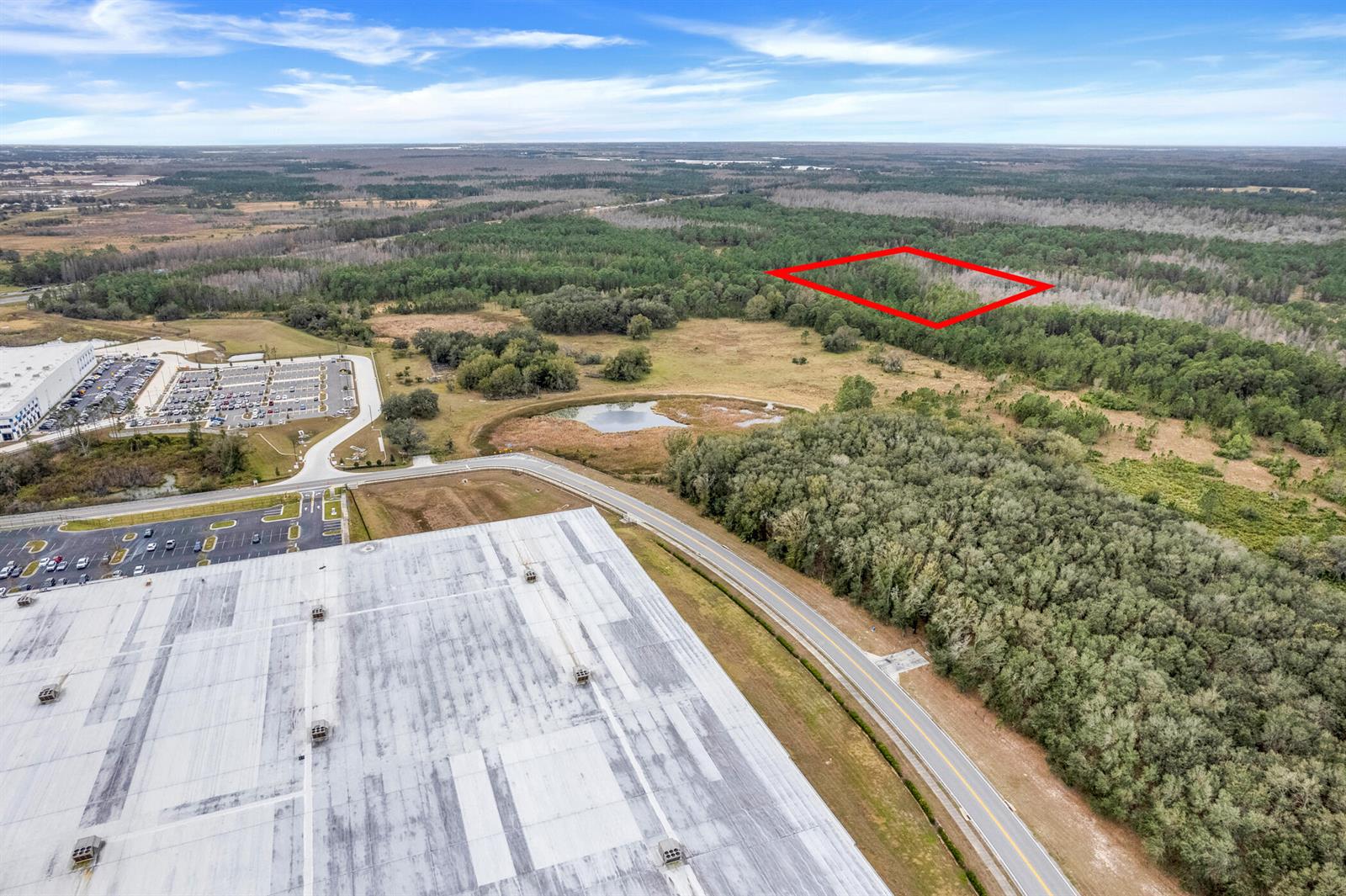 An aerial view shows a large warehouse, a parking lot, and a forested plot outlined red — 000 No Street, FL 33868, FL