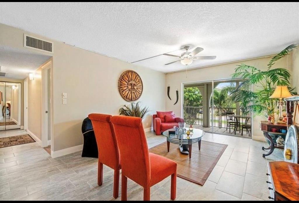A living room with orange chairs, a glass coffee table, and a balcony view — 250 NE 20TH STREET UNIT 3030, BOCA RATON, FL
