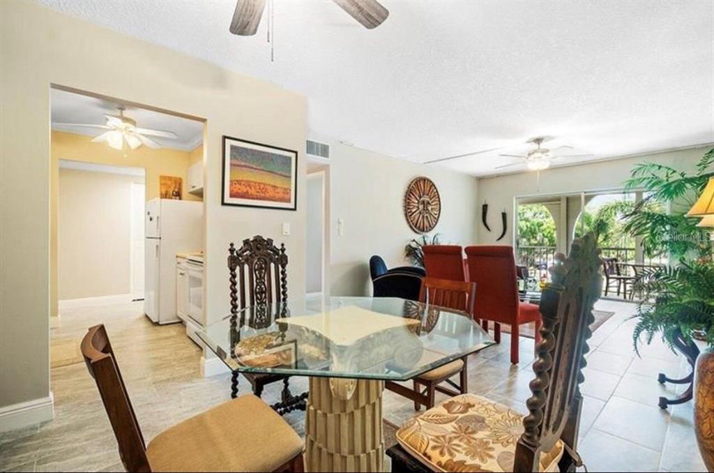 A dining area with a glass-topped table, ornate wooden chairs, and an adjacent kitchen — 250 NE 20TH STREET UNIT 3030, BOCA RATON, FL