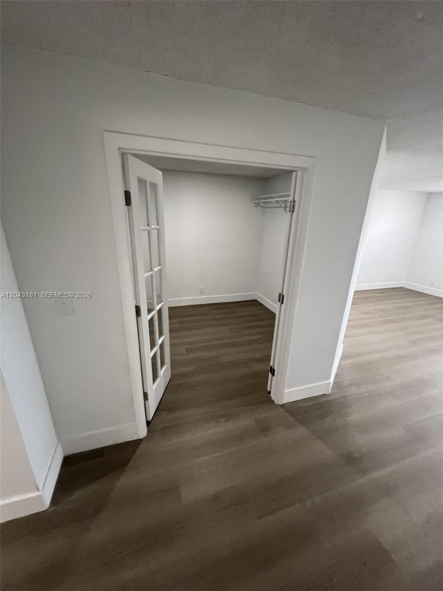 A closet with French doors and a wire shelf sits off a room with wood-look flooring — 22605 SW 66th Ave # 403, Boca Raton FL 33428, BOCA RATON, FL