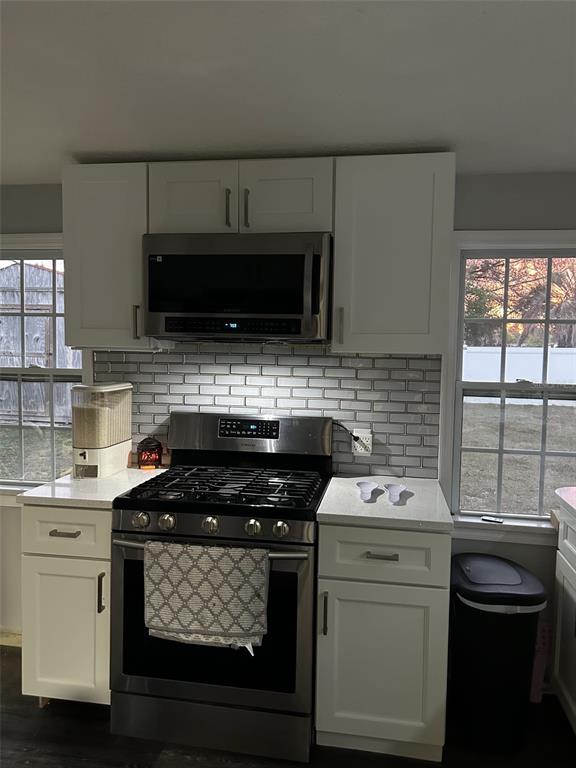 A kitchen features white cabinets, a stainless steel gas range, and a gray subway tile backsplash — 1222 STILLWATER AVENUE, DELTONA, FL