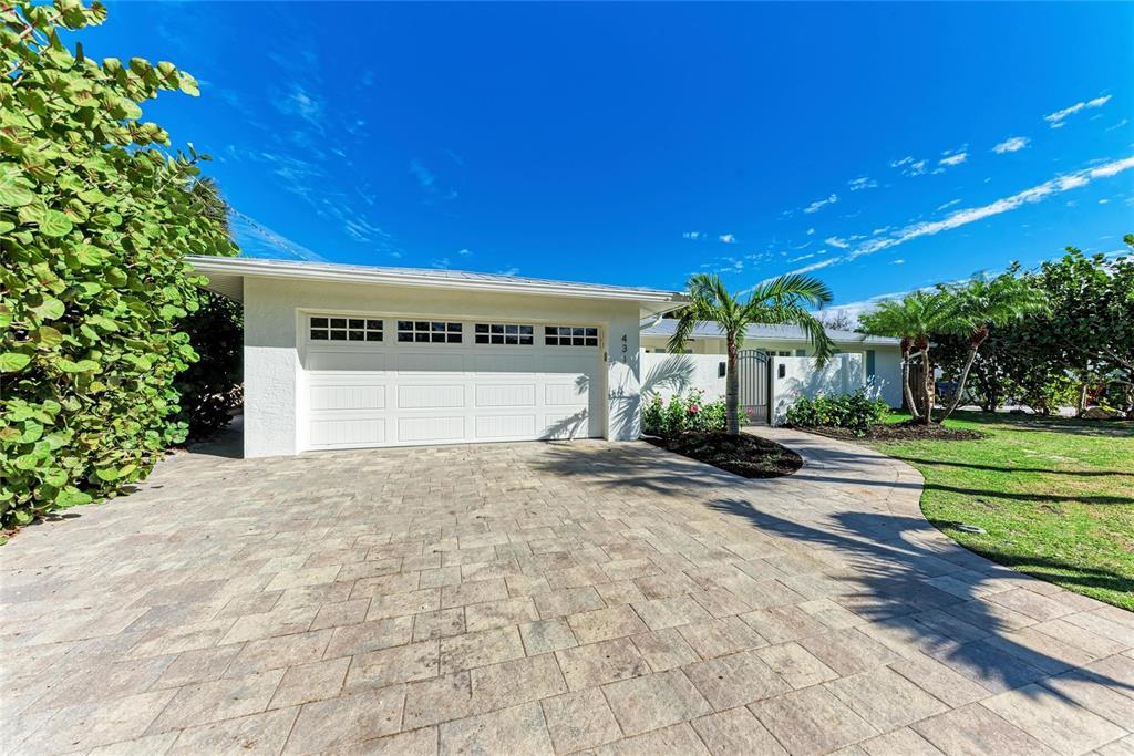 A white house with a two-car garage and a paved driveway under a blue sky — 431 ISLAND CIRCLE, SARASOTA, FL