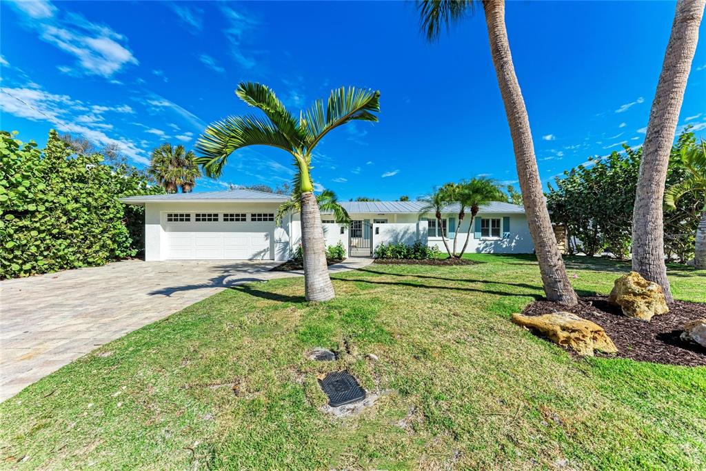 A single-story white house with a garage and palm trees sits on a grassy lot — 431 ISLAND CIRCLE, SARASOTA, FL
