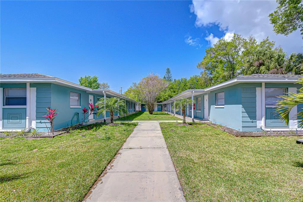 A concrete walkway leads between two single-story teal apartment buildings with grassy lawns — 3017 49TH STREET S UNIT 6, GULFPORT, FL