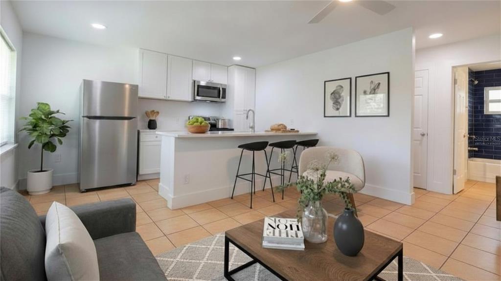 A kitchen and living area with white cabinets, stainless steel appliances, and tile flooring — 3017 49TH STREET S UNIT 6, GULFPORT, FL