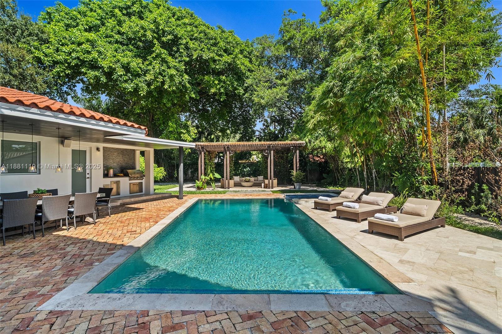 A backyard features a rectangular swimming pool, a patio with dining furniture, and a pergola — 575 Bay Point Rd, Miami FL 33137, MIAMI, FL