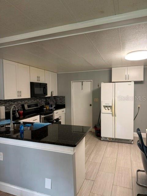 A kitchen features white cabinets, black countertops, a stainless steel refrigerator, and light-colored tile flooring — 6907 GIBRALTAR ROAD, ORLANDO, FL