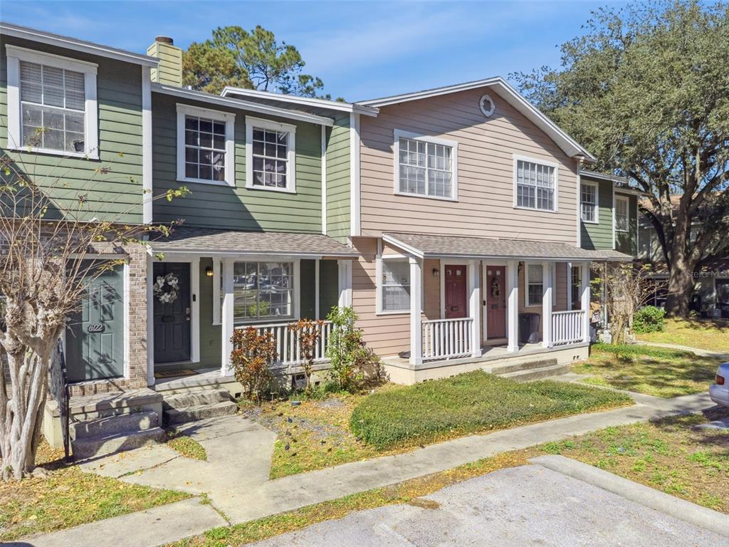 A row of two-story townhouses with green and tan siding, front porches, and small yards — 6924 WOODLAKE UNIT 104, ORLANDO, FL
