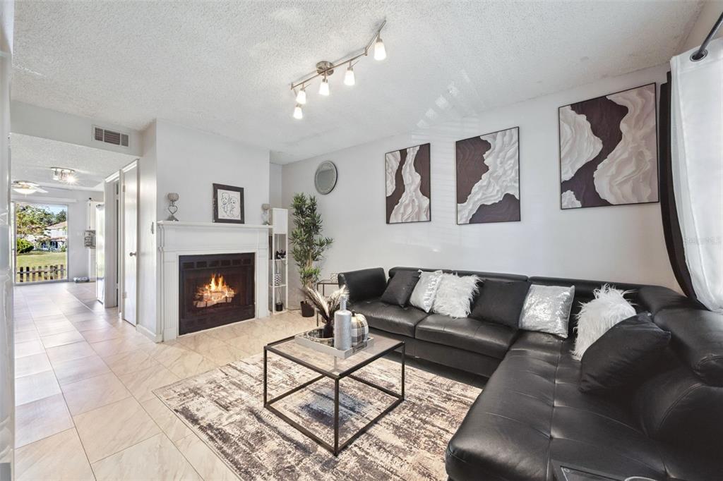 A living room features a fireplace, a black sectional sofa, and a glass coffee table — 6924 WOODLAKE UNIT 104, ORLANDO, FL