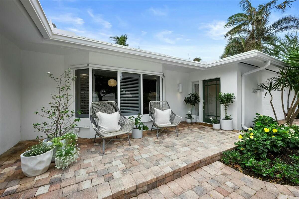 A paved patio with two chairs sits in front of a white house with a door — 232 Cove Place, Jupiter FL 33469, JUPITER, FL