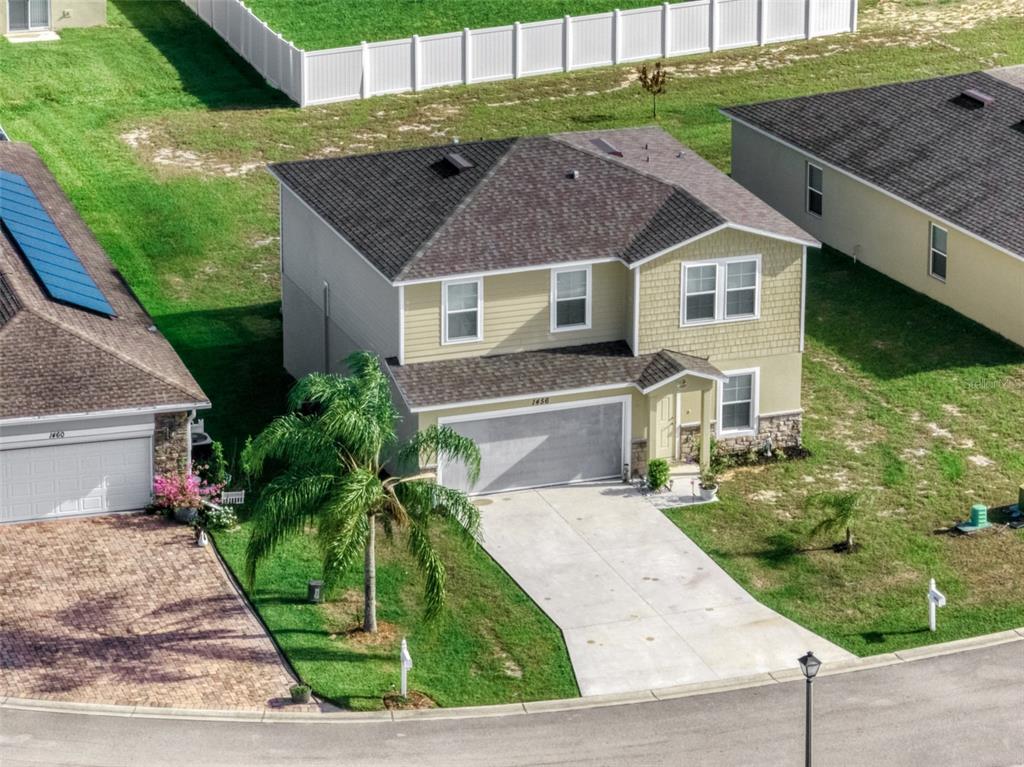A two-story house with a beige garage, stone accents, and a concrete driveway at sunset — 1456 STONE RIDGE CIRCLE, SEBRING, FL