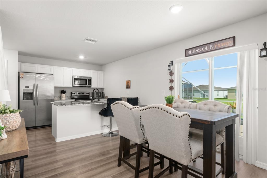 A kitchen with white cabinets and stainless steel appliances opens to a dining area — 1456 STONE RIDGE CIRCLE, SEBRING, FL