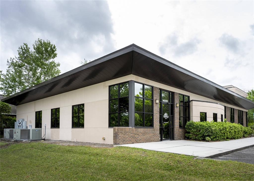 A single-story commercial building with a flat roof, brick accents, and a glass entrance door — 1445 E MITCHELL HAMMOCK ROAD UNIT 1, OVIEDO, FL