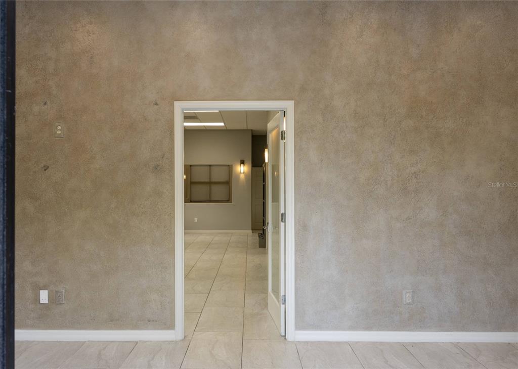A doorway leads from a room with textured tan walls into an adjacent office space — 1445 E MITCHELL HAMMOCK ROAD UNIT 1, OVIEDO, FL