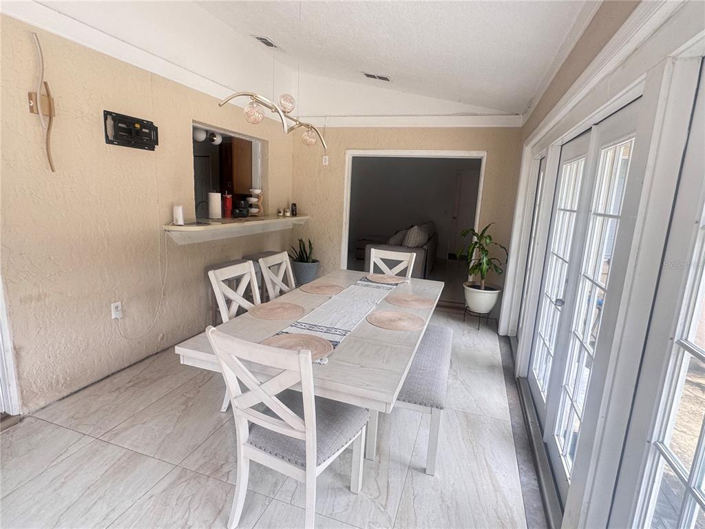 A dining room features a light wood table, white chairs, a bench, and tile flooring — 304 SHADOW OAK DRIVE, CASSELBERRY, FL