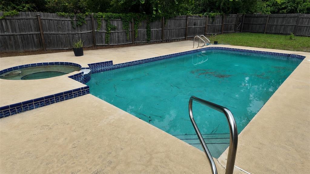 A rectangular swimming pool with an attached spa sits on a concrete deck near a fence — 304 SHADOW OAK DRIVE, CASSELBERRY, FL