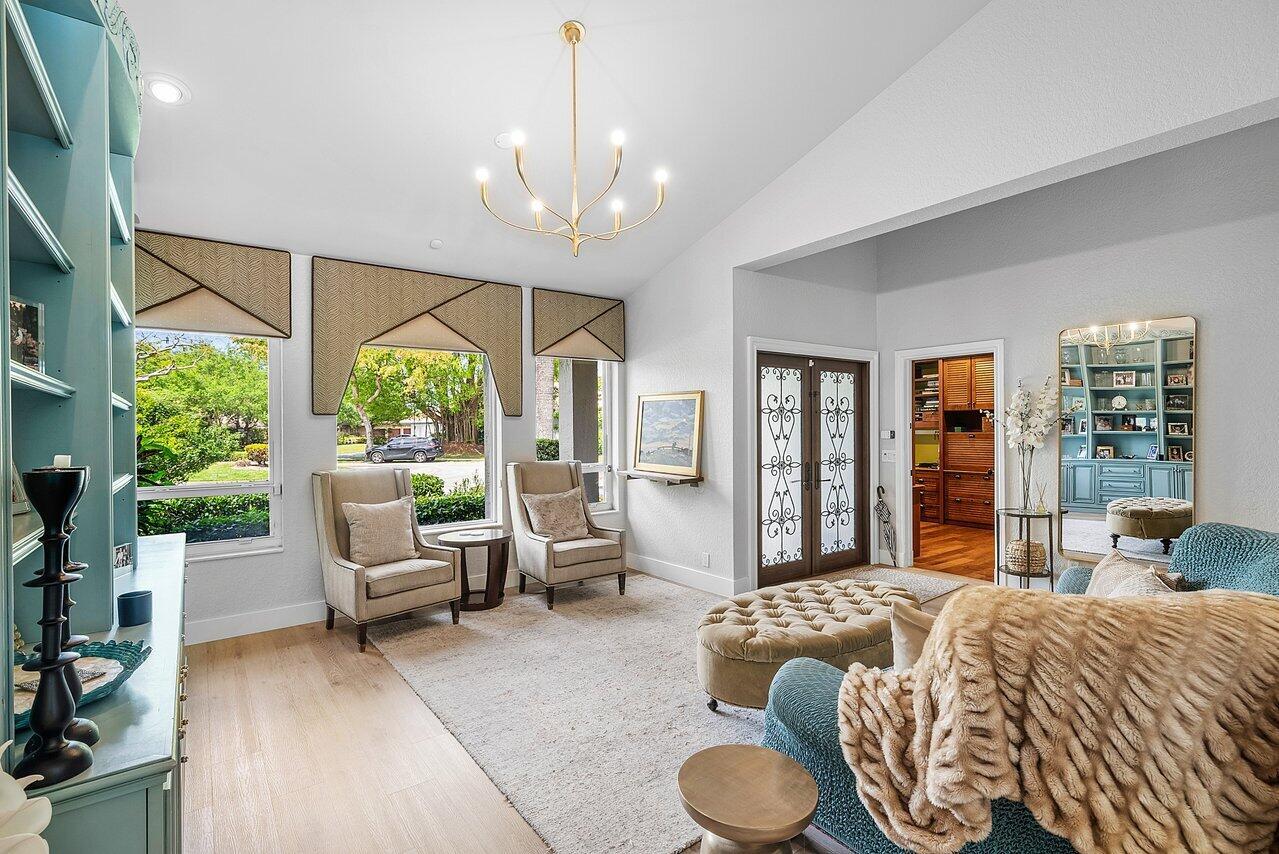 A bright living room features two armchairs, a large ottoman, and a blue built-in bookshelf — 3010 Hampton Circle, Boca Raton FL 33434, BOCA RATON, FL